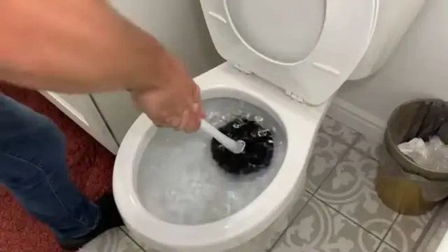 A hand using a toilet brush in a bowl